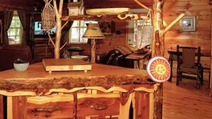 L’intérieur d’un chalet rustique en bois, avec un bar en bois, un téléviseur et une table à manger.