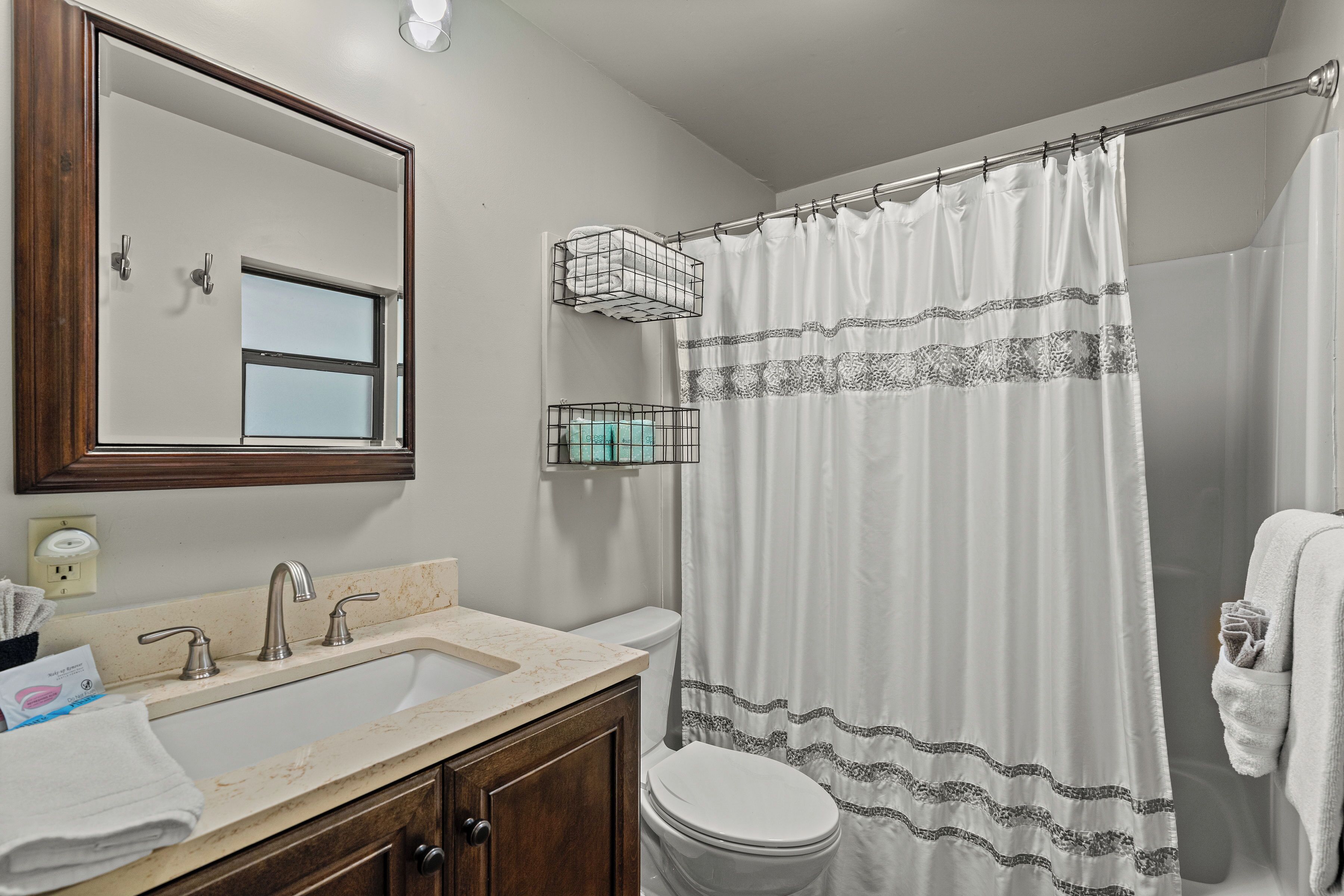 A bathroom with a sink, mirror, toilet, and shower curtain.