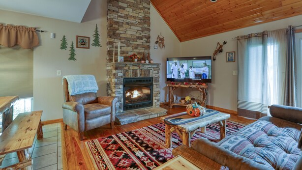 Ein gemütliches Wohnzimmer mit Kamin aus Stein, Holzboden und einem Fernseher.