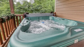 Ein Whirlpool auf einer Holzterrasse mit Blick auf Bäume.