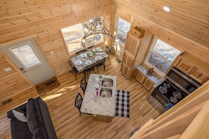 A compact kitchen with wooden walls, a dining area, and a large window.