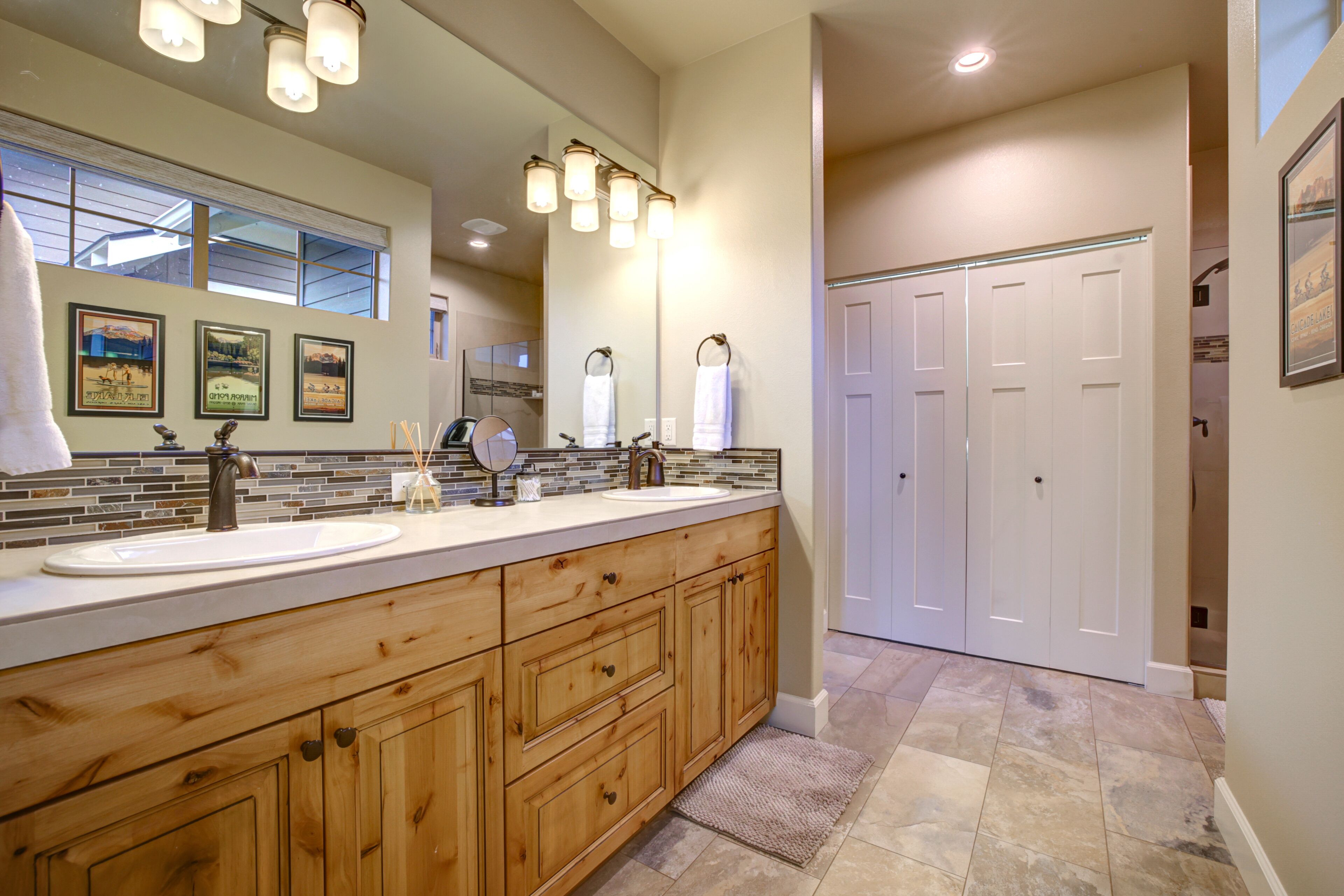 A bathroom with a large wooden vanity, two sinks, a mirror, and a tiled floor.