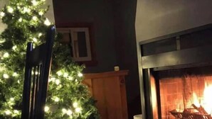 Ein gemütliches Wohnzimmer mit Kamin, Weihnachtstannen und Essbereich.