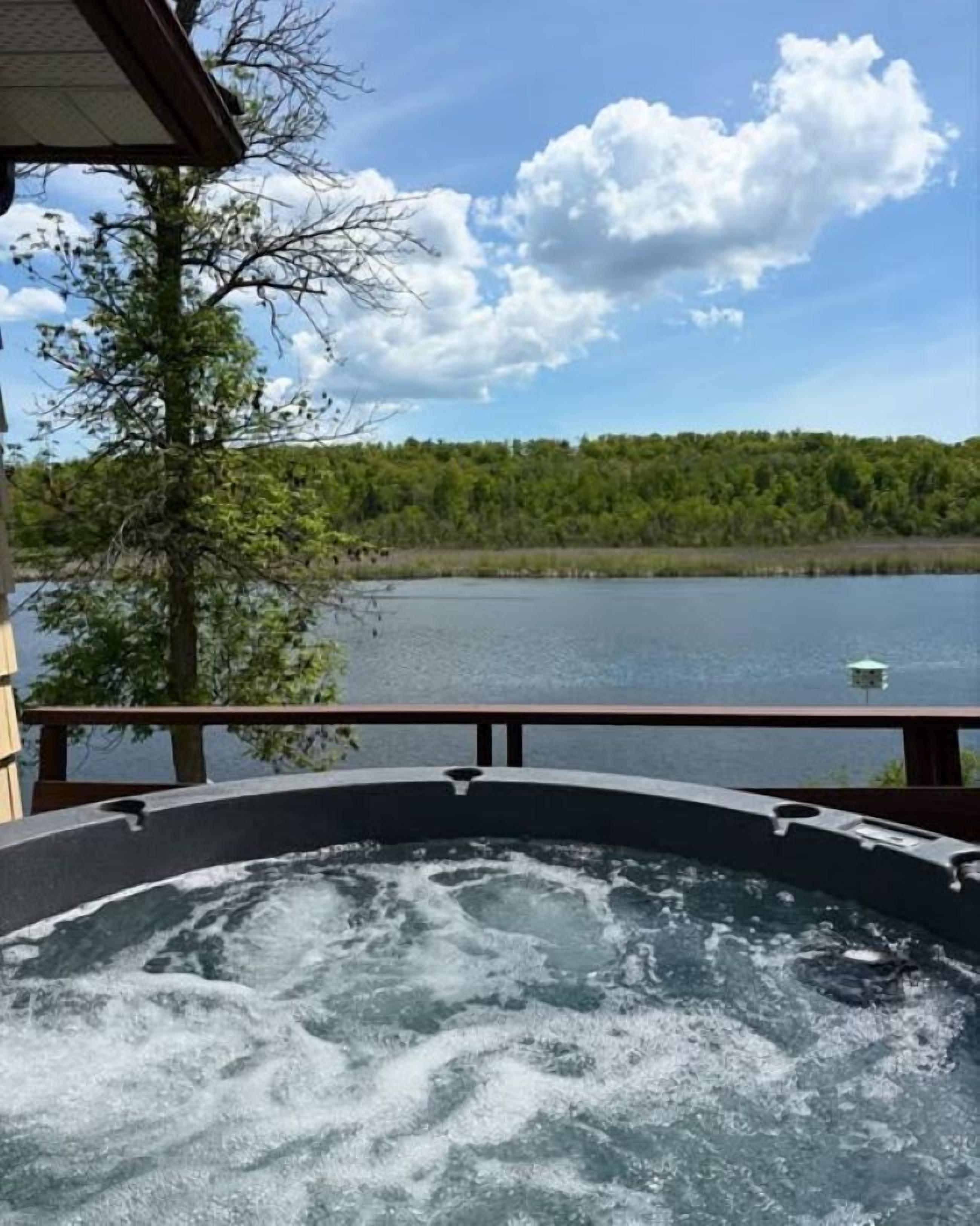 Un bain à remous avec vue sur un lac et une forêt.