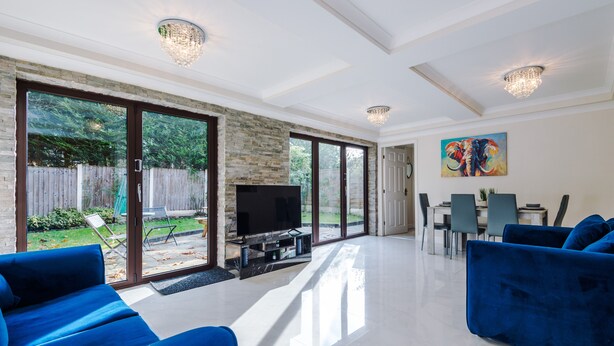Un salón amplio con un televisor grande, sofás azules y un comedor con sillas y una mesa.