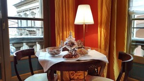 A dining table with a white tablecloth, a glass top, and a decorative centerpiece. - Palazzo di Alcina-Residenza D'Epoca (Bologna)