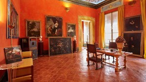 A room with red walls, a wooden table, and framed paintings. - Palazzo di Alcina-Residenza D'Epoca (Bologna)