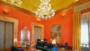 A room with a large chandelier, a piano, and a painting on the wall. - Palazzo di Alcina-Residenza D'Epoca (Bologna)