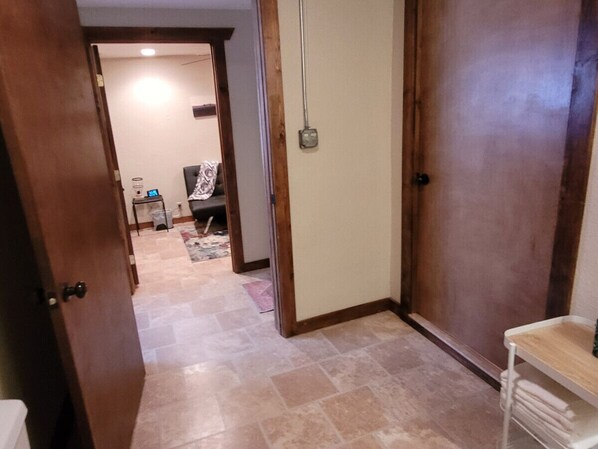 A hallway with a tiled floor, wooden doors, and a small table with a stack of papers.