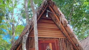 A rustic wooden hut with a thatched roof, a wooden door, and a small porch area. - Hotel y Eco-Cabañas Azul María Bacalar (Bacalar)