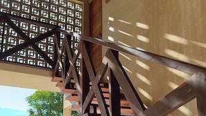 A wooden staircase with a geometric railing design, leading to an outdoor area with a view of the sea and a fire extinguisher mounted on the wall. - Hotel y Eco-Cabañas Azul María Bacalar (Bacalar)