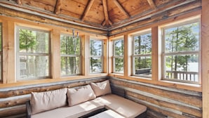 A log cabin interior with a wooden bench and large windows offering a view of the surrounding forest. - Lakefront Pine Retreat in Lewiston - 1 Mile from Garland Golf Resort (Lewiston)