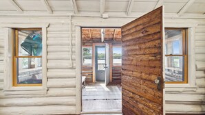A log cabin interior with a wooden door leading to a porch. - Lakefront Pine Retreat in Lewiston - 1 Mile from Garland Golf Resort (Lewiston)