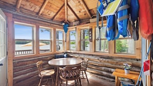 A log cabin interior with a wooden dining table and chairs, large windows, and a view of the outdoors. - Lakefront Pine Retreat in Lewiston - 1 Mile from Garland Golf Resort (Lewiston)