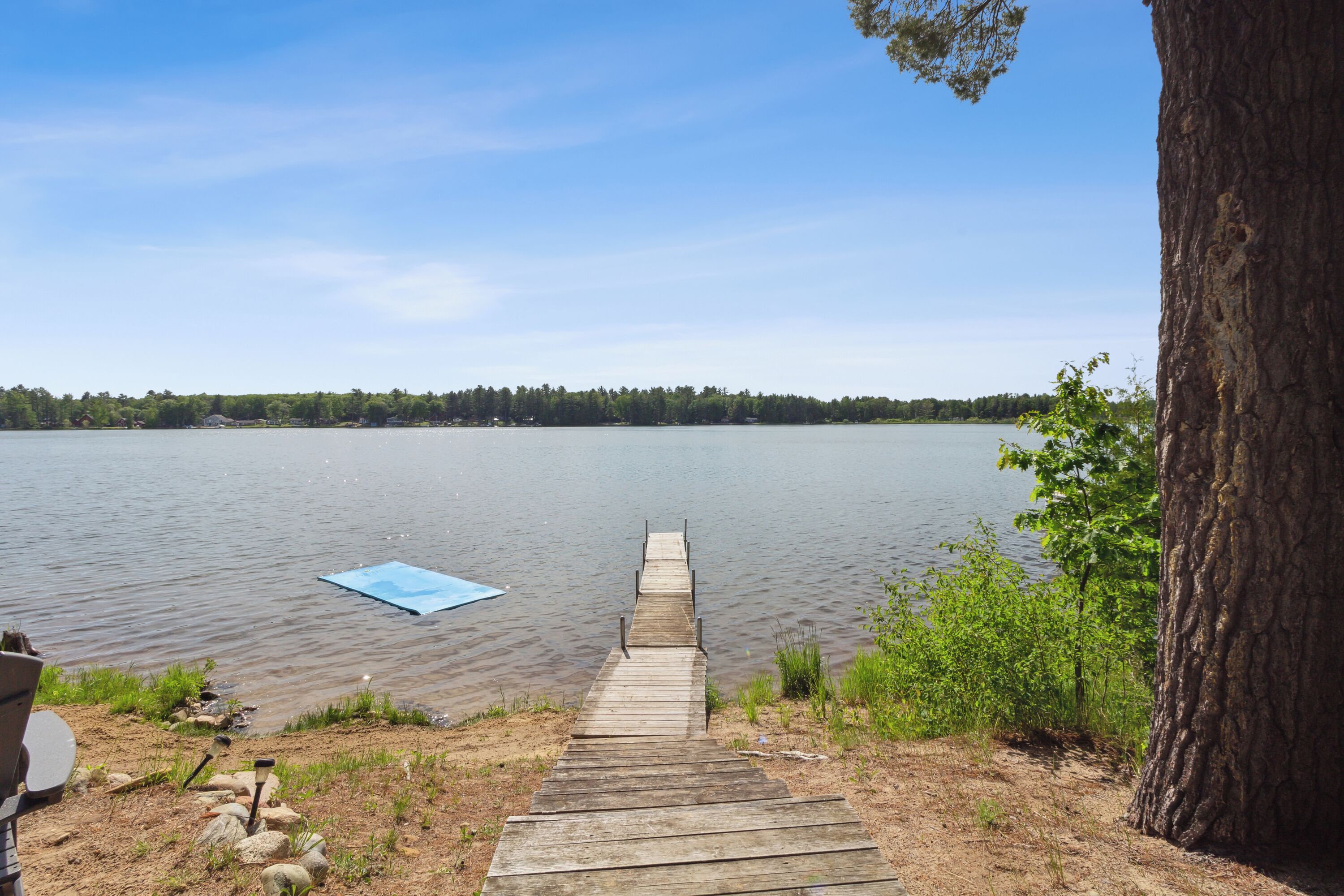 A wooden dock leading to a calm lake with a clear sky.