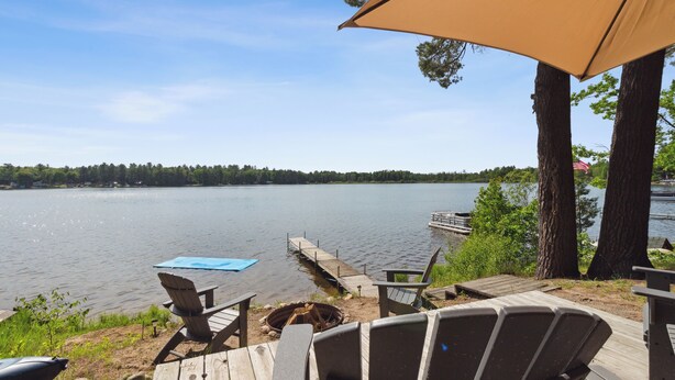 A lakeside deck with wooden chairs and a blue table, overlooking a calm lake. - Lakefront Pine Retreat in Lewiston - 1 Mile from Garland Golf Resort (Lewiston)