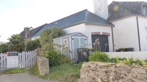 A building with a stone wall, a wooden fence, and a small shed.