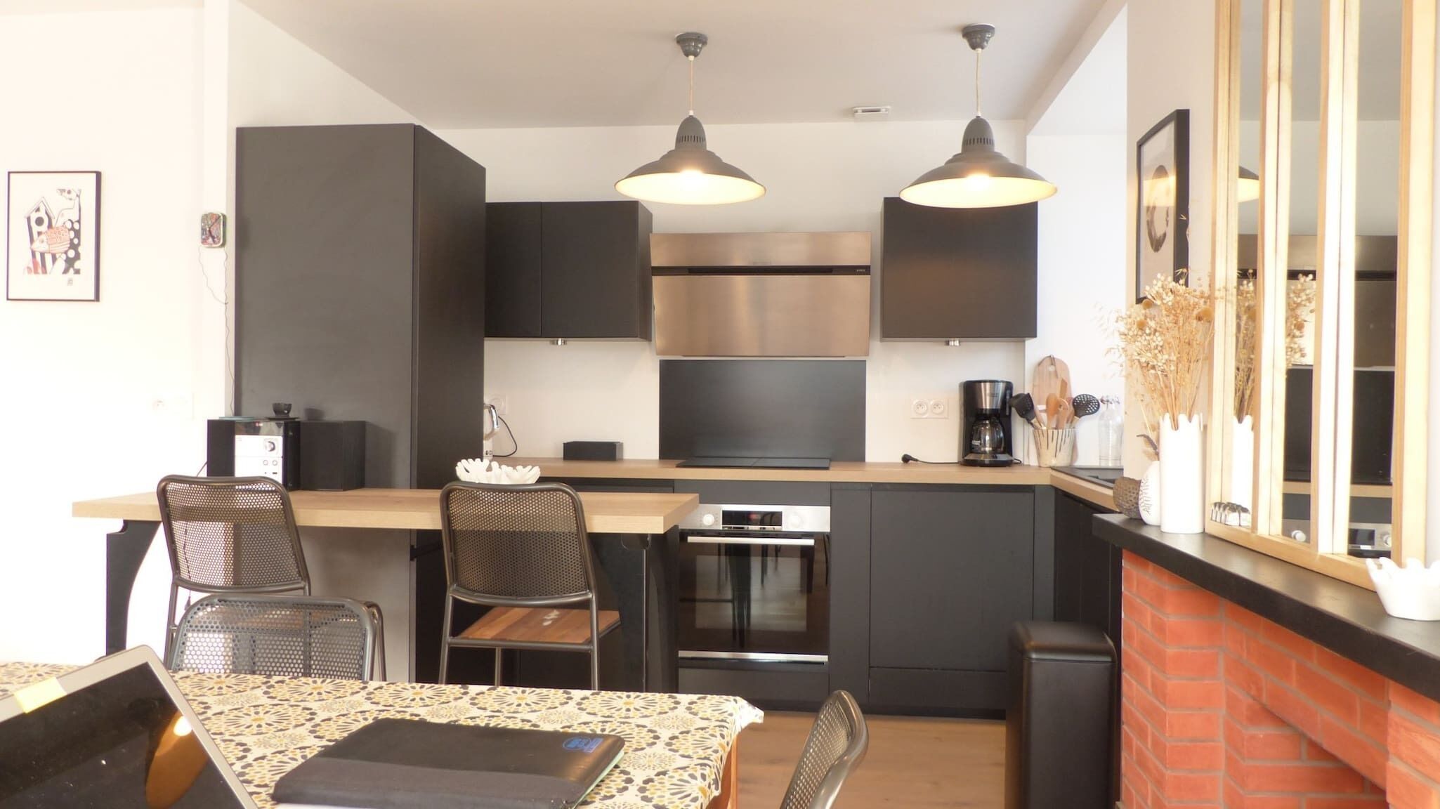 Una cocina moderna con armarios oscuros, una isla central e iluminación colgante.