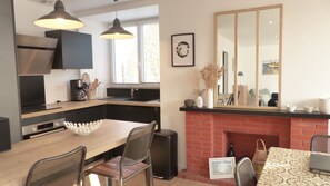 A modern kitchen with a dining area, a fireplace, and a large mirror.