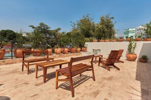 Une terrasse extérieure aménagée avec des meubles en bois, des plantes en pot et une vue sur le panorama urbain.