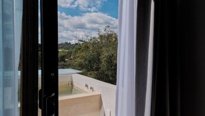 A view from a window with a bathtub and a pool, surrounded by greenery and a clear sky. - Casona Juárez - Porfirio / private plunge pool (Oaxaca de Juárez)