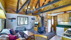 Ein gemütliches Blockhaus-Interieur mit Wohnbereich, Kamin, Küche und Holzbalken.
