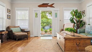 A cozy living room with a wicker chair, a wooden coffee table, and a large plant.