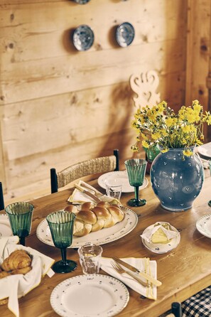 Ein Holztisch mit Tellern, Gläsern und einer Blumenvase.