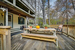 Eine Holzterrasse mit Picknicktisch und Bänken, umgeben von einem Holzzaun und Bäumen.