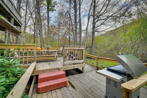 Eine Holzterrasse mit Grill, Sitzgelegenheit und einer überdachten Holzhütte.