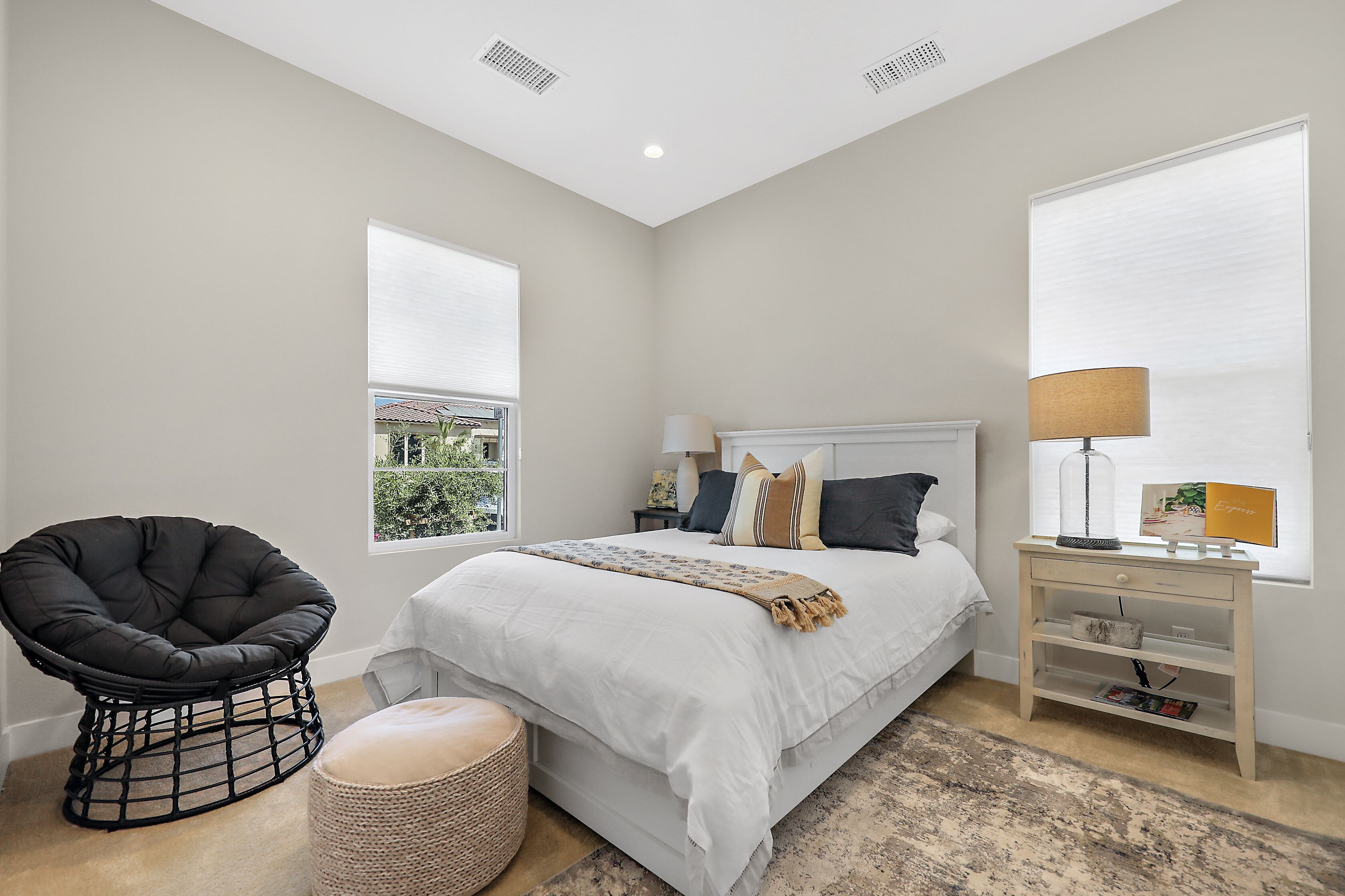 A bedroom with a bed, a chair, a nightstand, and a window.