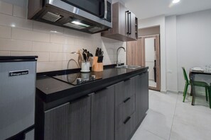 A modern kitchen with a built-in microwave, stainless steel range hood, and a black countertop. - Rooftop Pool w/Lounge Area-Studio Sleeps 2 A9 (Oranjestad)
