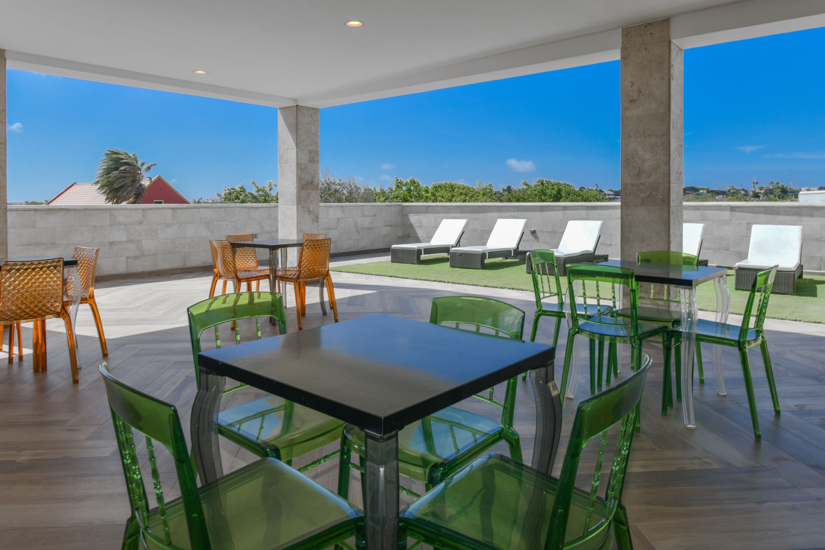 A rooftop terrace with a table and chairs, lounge chairs, and a view of the landscape.