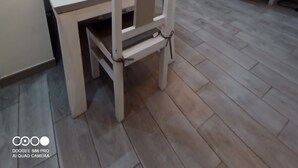 Ein Essbereich mit weißem Tisch und Stühlen, einer Couch mit Kissen und einer Treppe, die zu einer anderen Ebene führt.