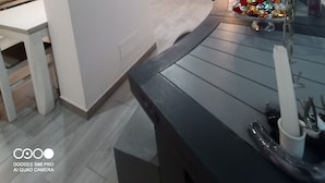 Eine moderne Küche mit weißen Schränken, ein Essbereich mit Tisch und Stühlen sowie ein Fenster mit Vorhängen.
