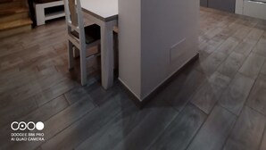 Eine moderne Küche mit weißen Schränken, einem eingebauten Backofen und einem Essbereich mit weißem Tisch und Stühlen.