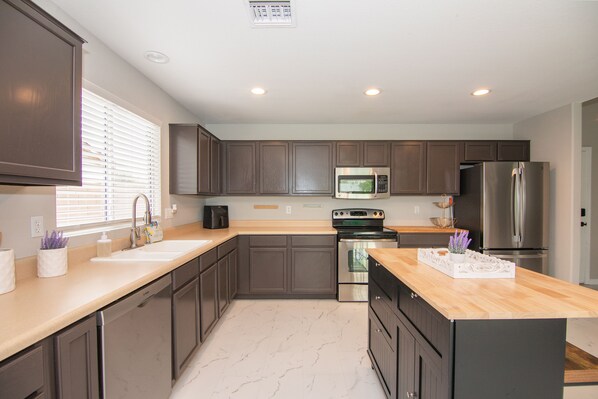 A modern kitchen with dark wood cabinets, stainless steel appliances, and a marble floor.