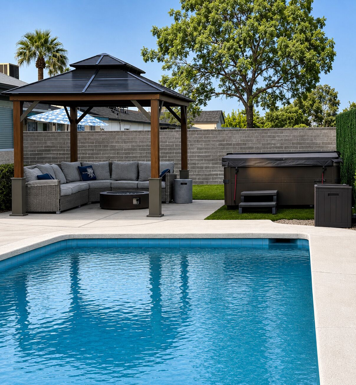 A swimming pool with a built-in hot tub, a covered seating area, and a patio with a sofa and outdoor furniture.