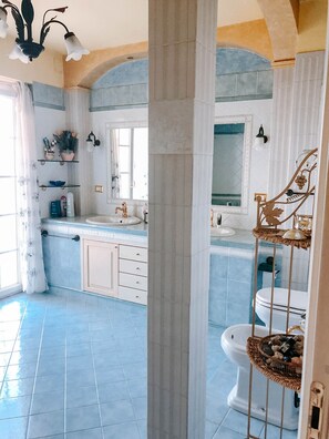 A bathroom with a blue tiled floor, a white sink, a mirror, and a toilet.
