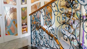 A staircase with ornate metal railings and a patterned glass door. - Alexander's Home (Collecorvino)