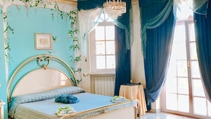 A bedroom with a bed, a chandelier, a window with curtains, and a radiator. - Alexander's Home (Collecorvino)