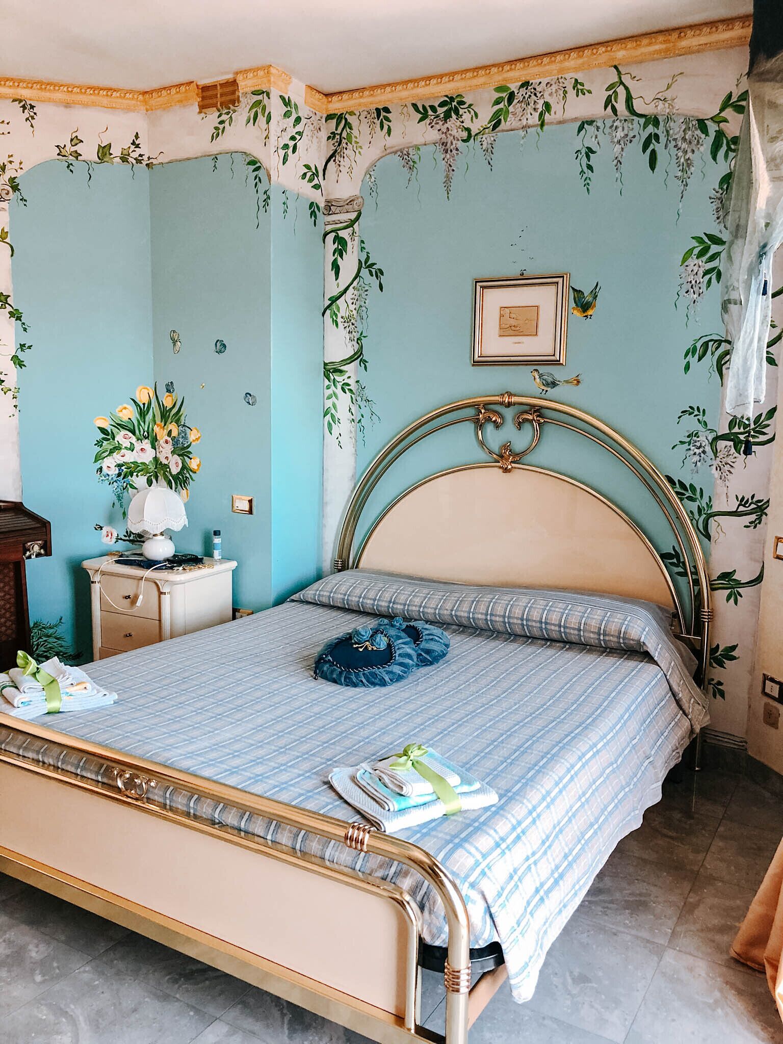 A bedroom with a bed, a nightstand, and a wall with floral wallpaper.
