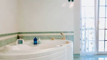 Un baño con una bañera independiente, un dispensador de jabón para manos y un cabezal de ducha.