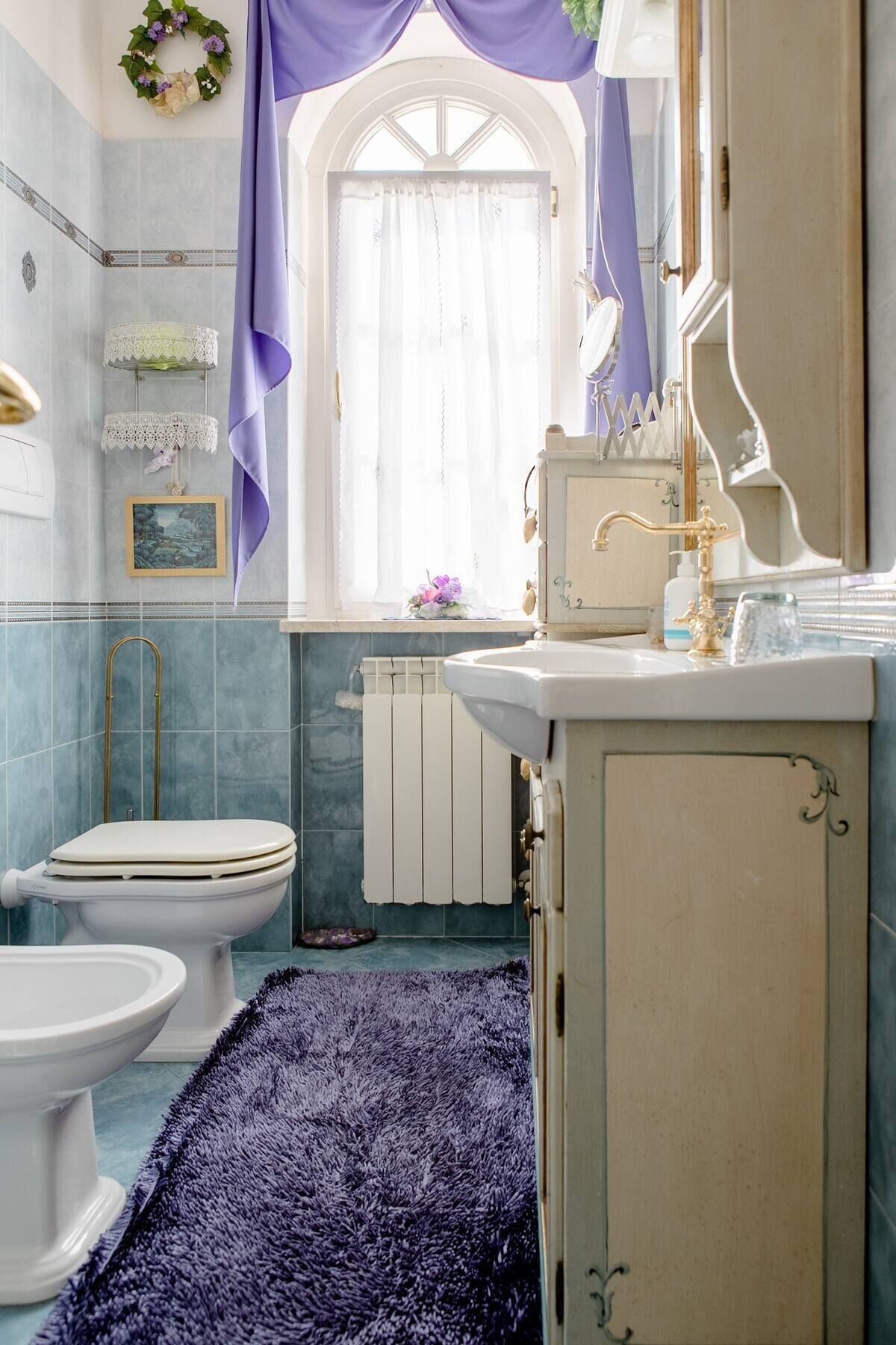 Une salle de bain avec des toilettes, un lavabo et une fenêtre avec des rideaux.