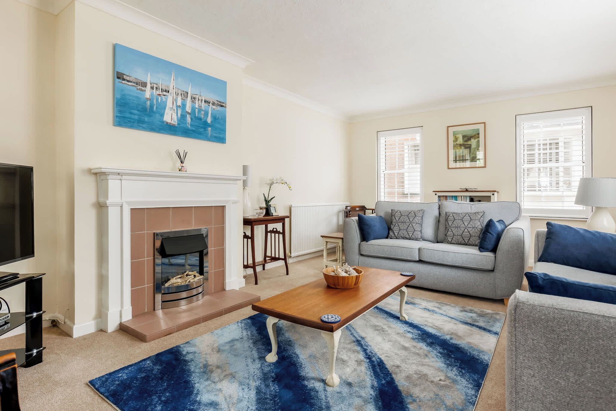 A living room with a fireplace, a sofa, a coffee table, and a painting on the wall.