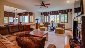 A spacious living room with a leather sofa, a wooden coffee table, and a fireplace. - Gavia Chalet - Mountain Views - Private Hot Tub - Loon Mtn - Kancamangus Highway (Lincoln)