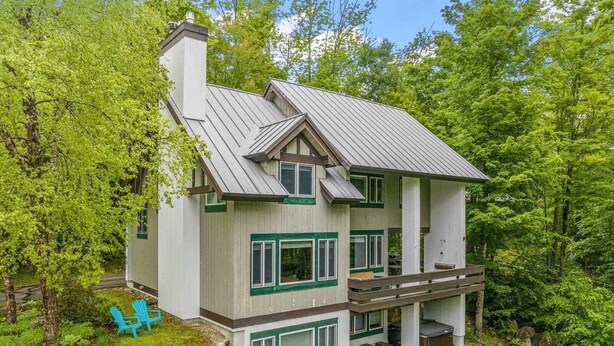 A two-story house with a metal roof, green window frames, and a deck. - Gavia Chalet - Mountain Views - Private Hot Tub - Loon Mtn - Kancamangus Highway (Lincoln)