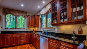 A kitchen with wooden cabinets, a black countertop, and a dishwasher. - Gavia Chalet - Mountain Views - Private Hot Tub - Loon Mtn - Kancamangus Highway (Lincoln)