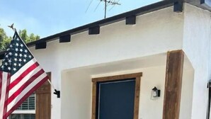 A house with a blue door, a potted plant in the front, and an American flag on the left.