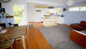 Un vaste espace de vie comprenant une table et des chaises en bois pour la salle à manger, une moquette grise et un canapé en cuir marron.